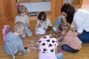 Dzieci z przedszkola układają puzzle w przestrzeni biblioteki