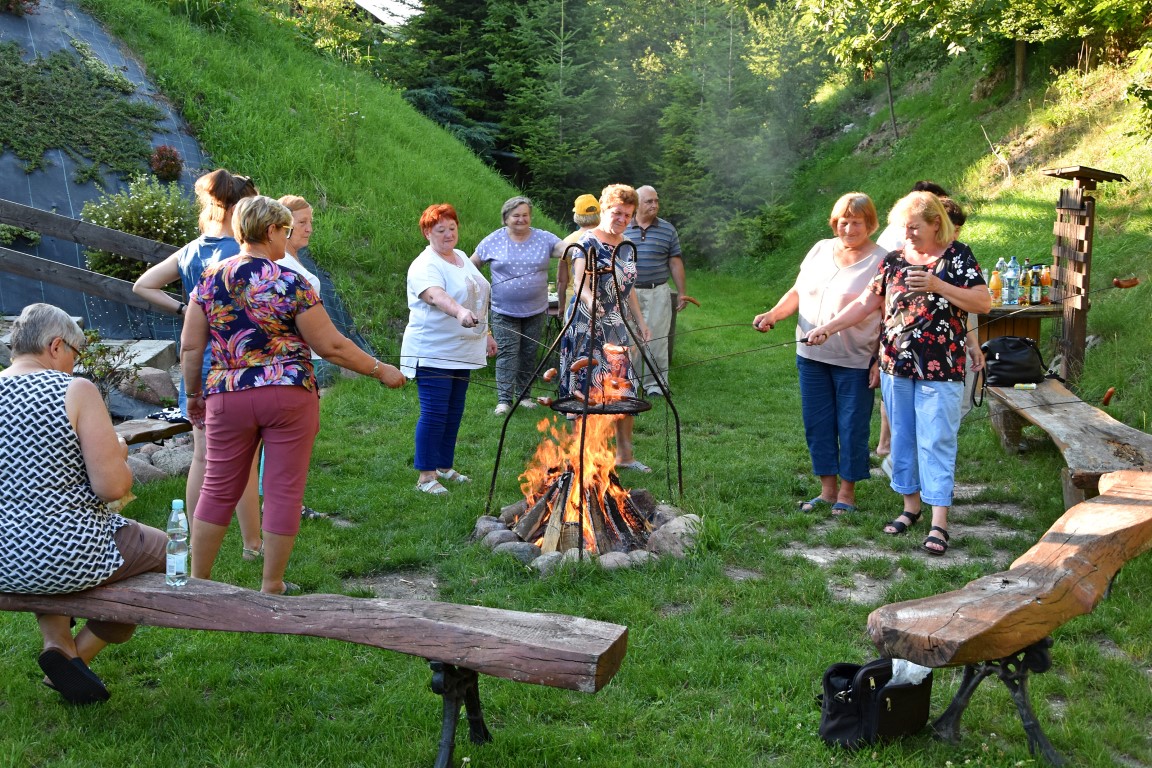Seniorzy podczas pieczenia kiełbasek przy ognisku