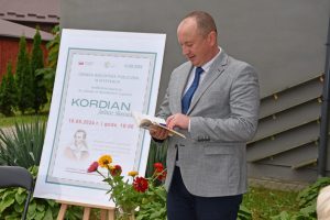 Bernard Błaszczuk – Wójt Gminy Wyryki podczas interpretacji wybranego utworu, w tle plakat wydarzeni oraz budynek GBP Wyryki