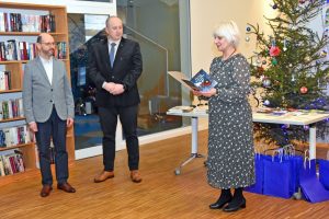 W przestrzeni biblioteki stoi Dyrektor GBP Wyryki Hanna Czelej, Wójt Gminy Wyryki Bernard Błaszczuk oraz Sekretarz Piotr Kazanecki. W tle widoczne jest drzewko świąteczne ozdobione kolorowymi bombkami i światełkami.