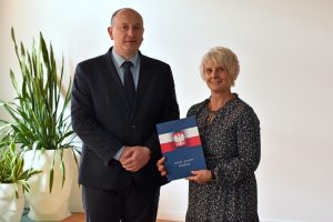 Wójt Gminy Wyryki stoi obok Dyrektor GBP Wyryki trzymającej w dłoniach list gratulacyjny