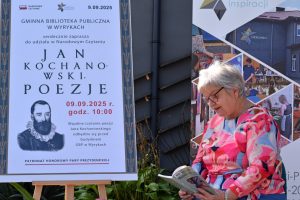 Kobieta czyta książkę obok plakatu Narodowego Czytania poezji Jana Kochanowskiego